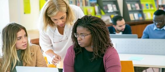 Two students and a teacher sitting at a laptop